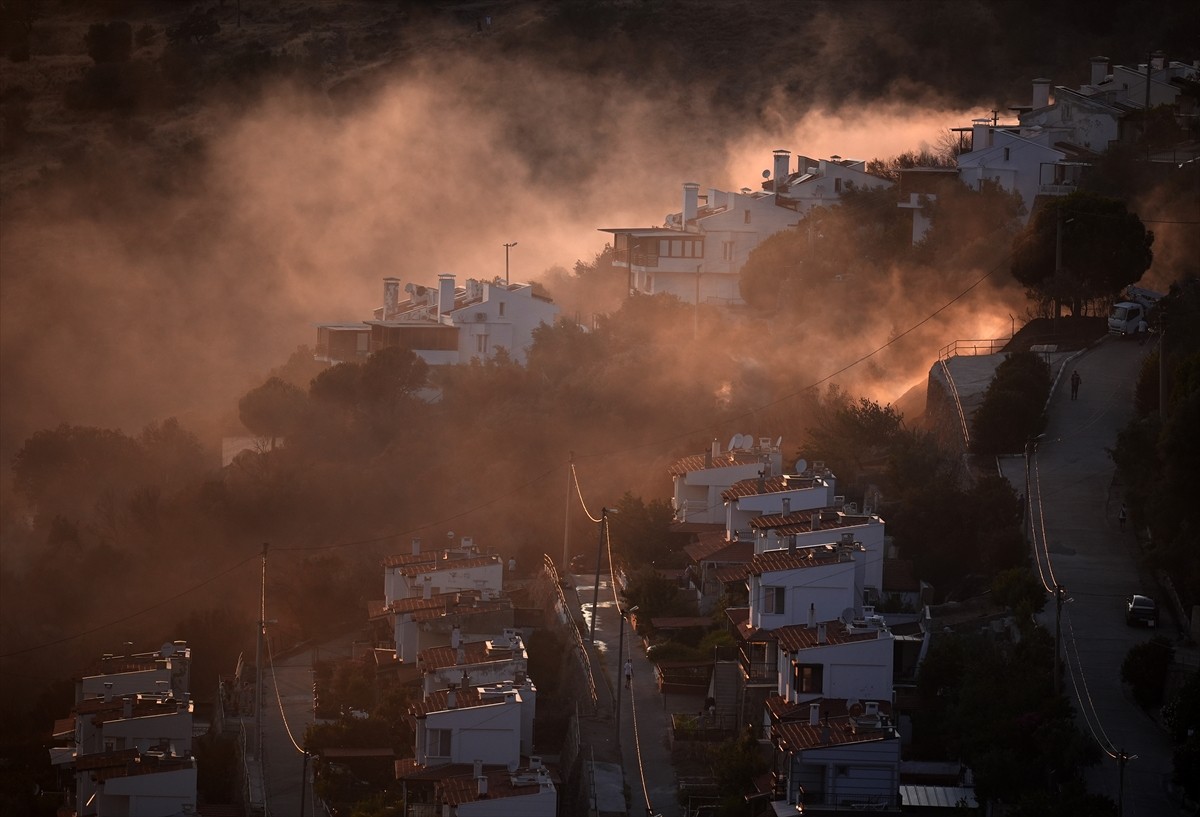 İzmir'in Dikili ilçesinde ormanlık alanda başlayan ve yerleşim yerlerine yaklaşan yangına havadan...