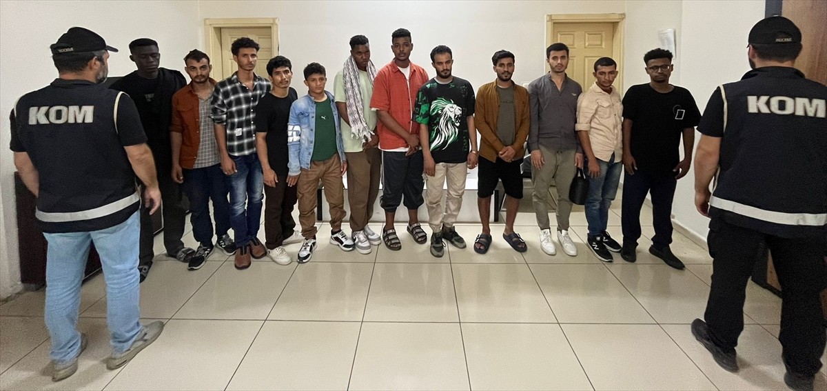 Balıkesir'in Burhaniye ilçesinde yakalanan 12 düzensiz göçmen ve 2 göçmen kaçakçılığı şüphelisi...