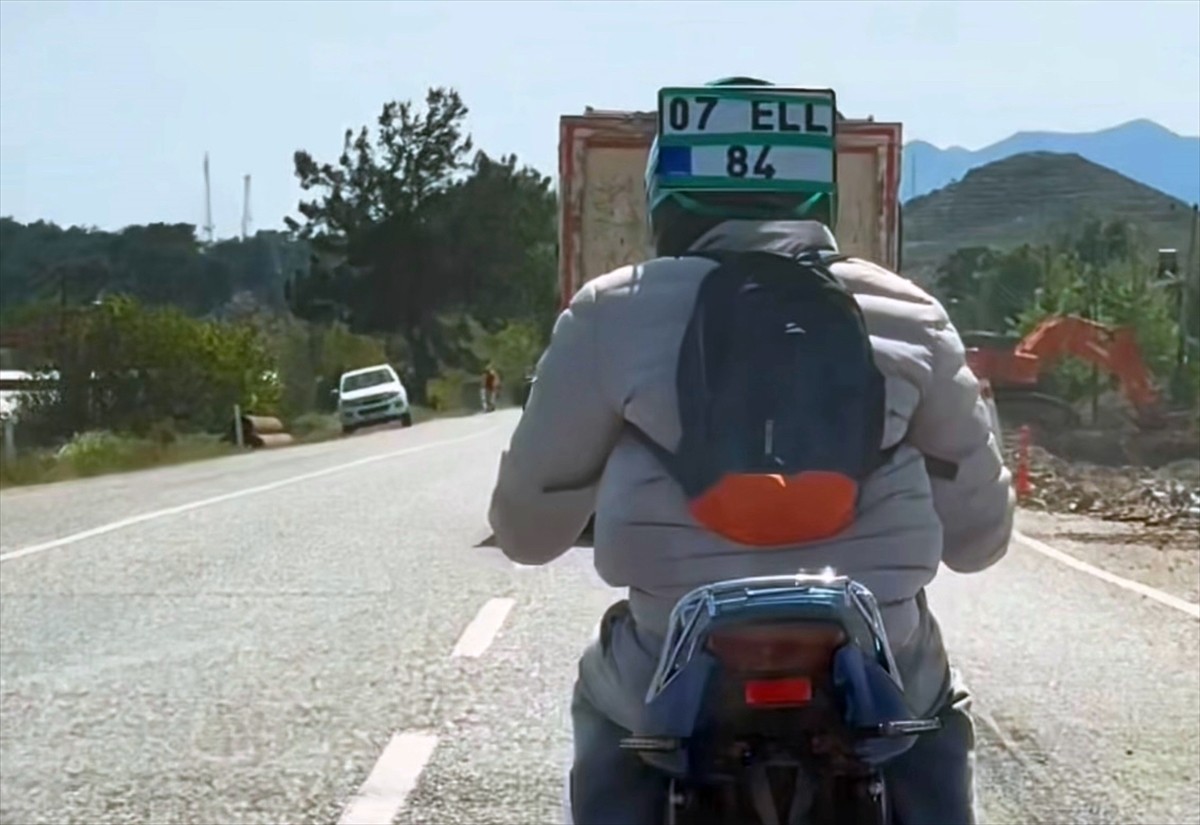 Muğla'nın Seydikemer ilçesinde bir sürücü, motosikletten düşen plakayı kaskına takarak trafikte...