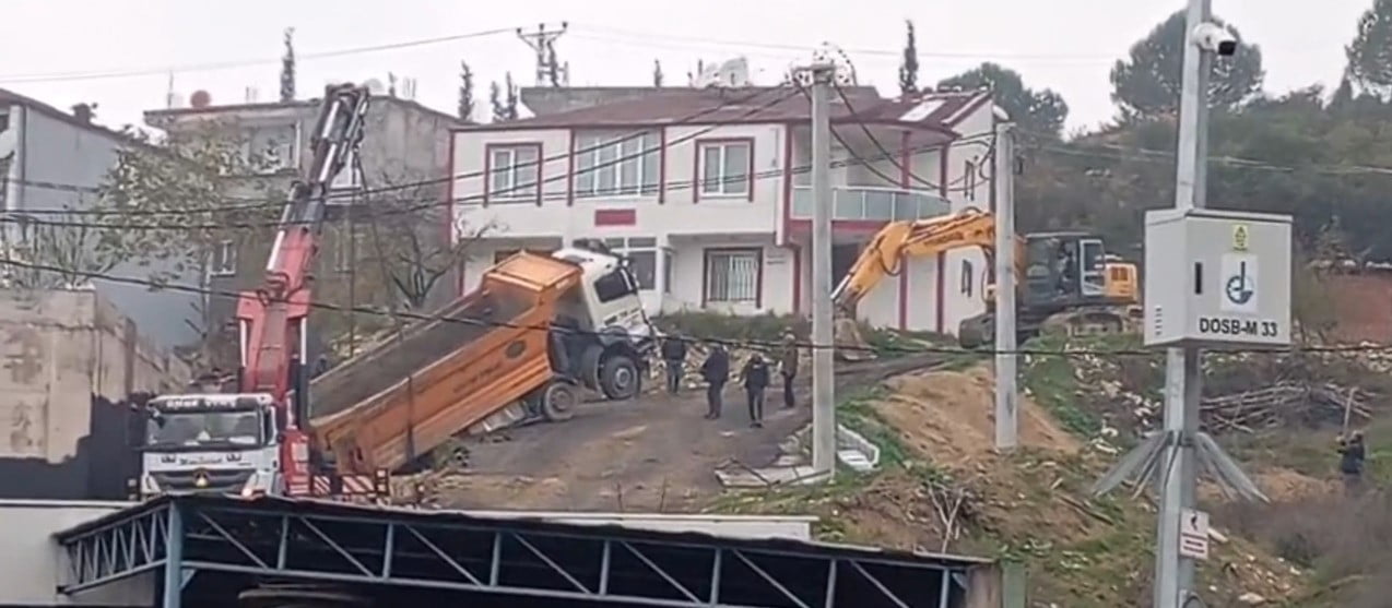 KOCAELİ'NİN DİLOVASI İLÇESİNDE HAFRİYAT DÖKÜMÜ SIRASINDA GERİ KAYARAK ASKIDA KALAN KAMYON, VİNÇ VE...