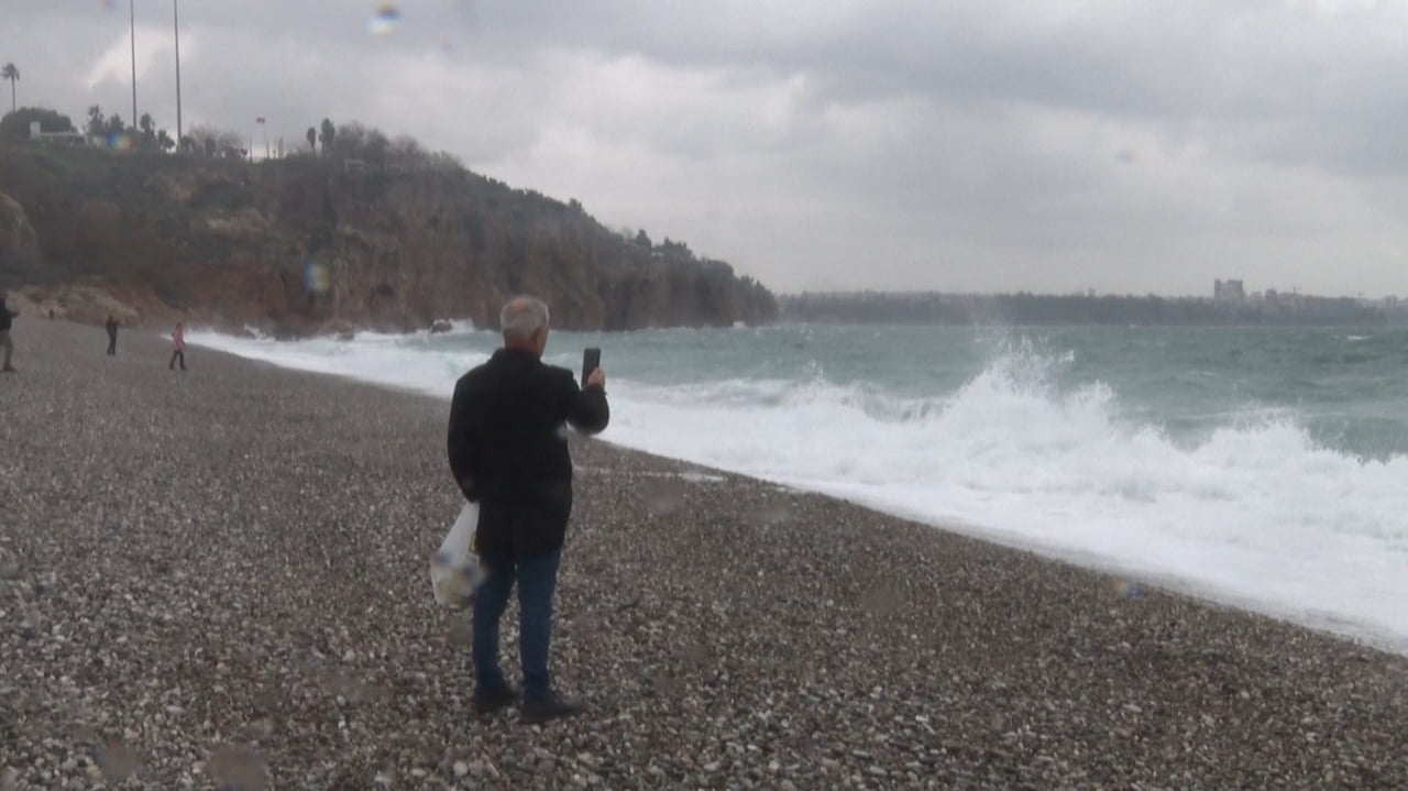 ANTALYA’DA ETKİLİ OLAN FIRTINALI HAVAYA RAĞMEN SAHİLE AKIN EDEN ANTALYALILAR, DALGALARIN...