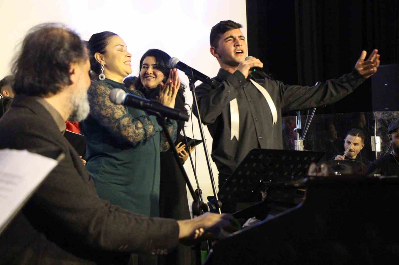 ORKESTRA EŞLİĞİNDE ŞARKILAR VE MARŞLAR SESLENDİREN HACIOĞULLARI İLE ÖĞRENCİLERİN PERFORMANSIYLA...